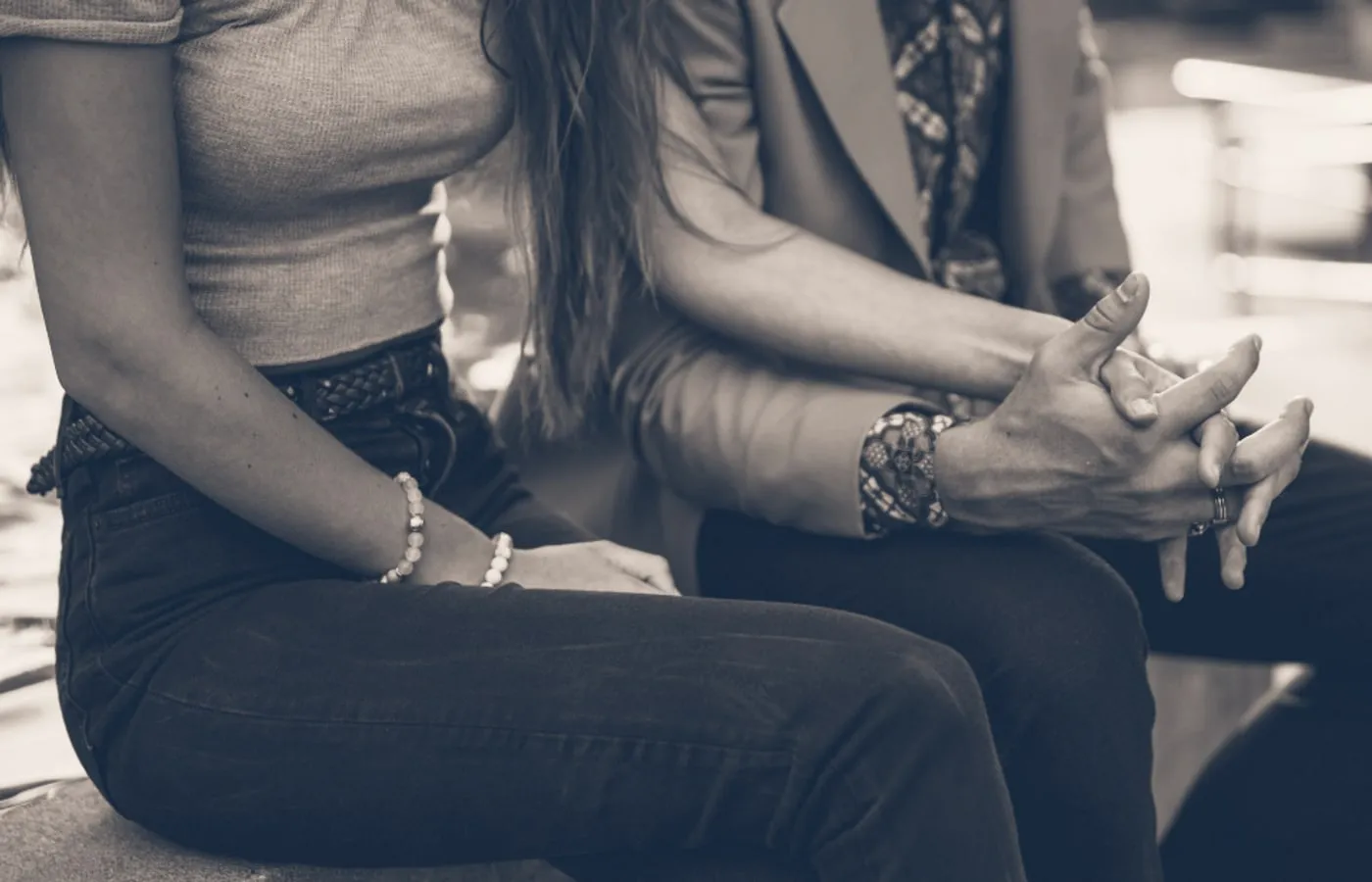 Two people sitting together, one hand resting on another